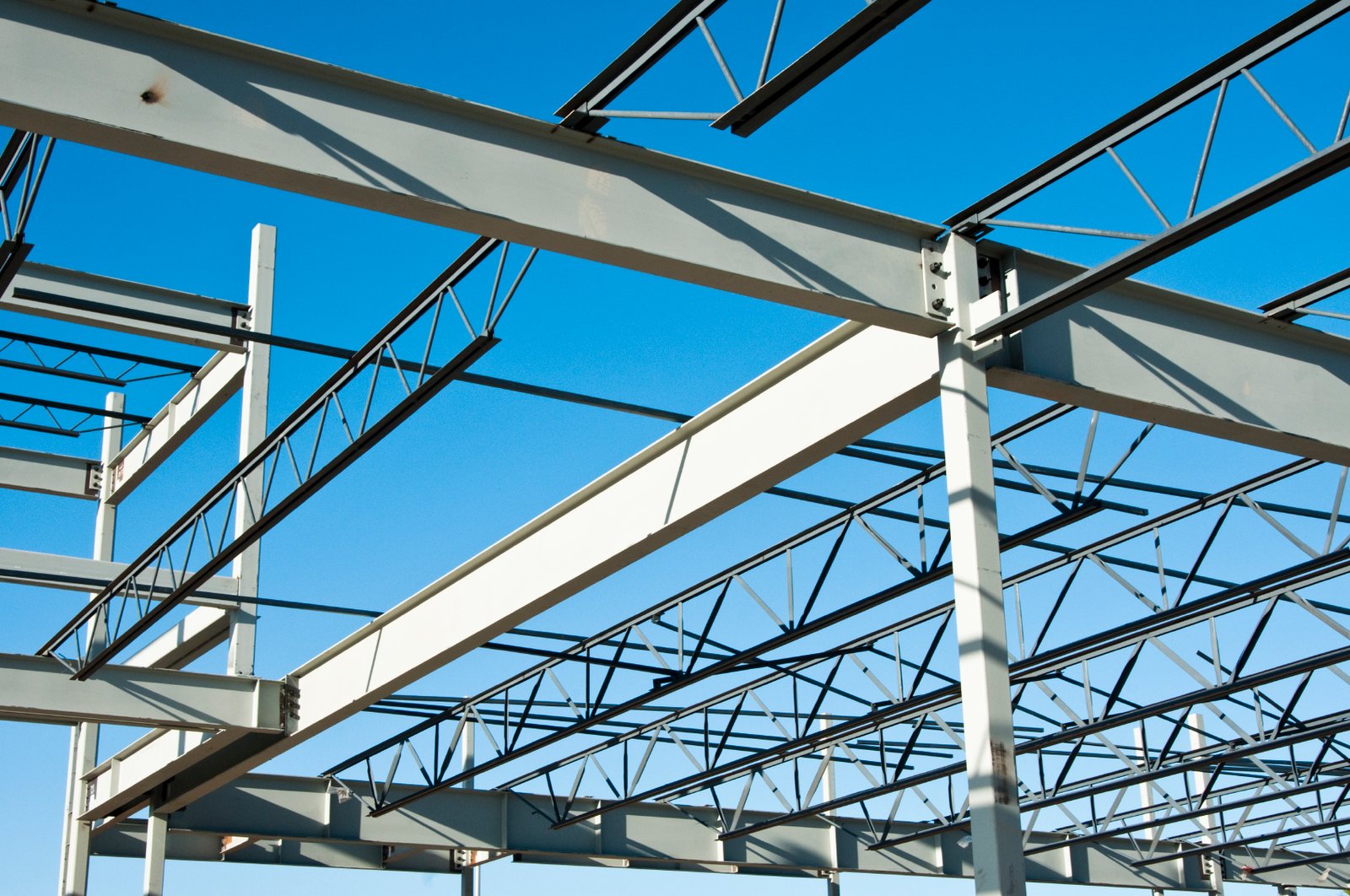 the structural steel structure of a new commercial building against a clear blue sky in the background