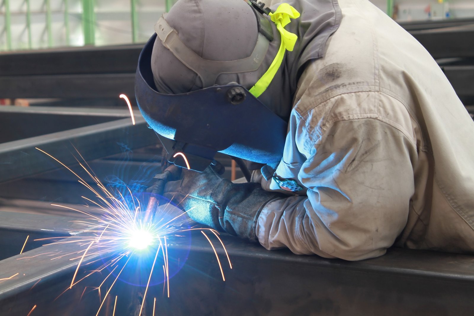 welder is welding steel structure with safety mask in factory
