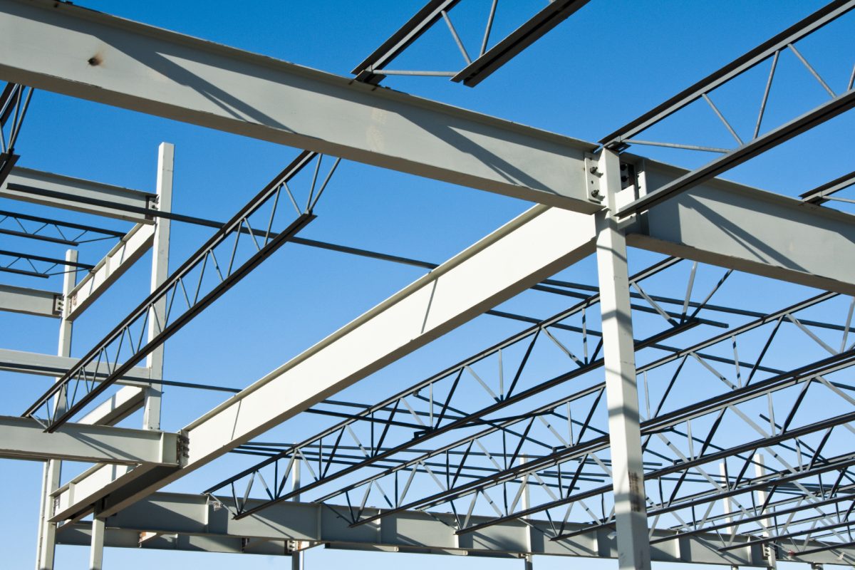 the structural steel structure of a new commercial building against a clear blue sky in the background