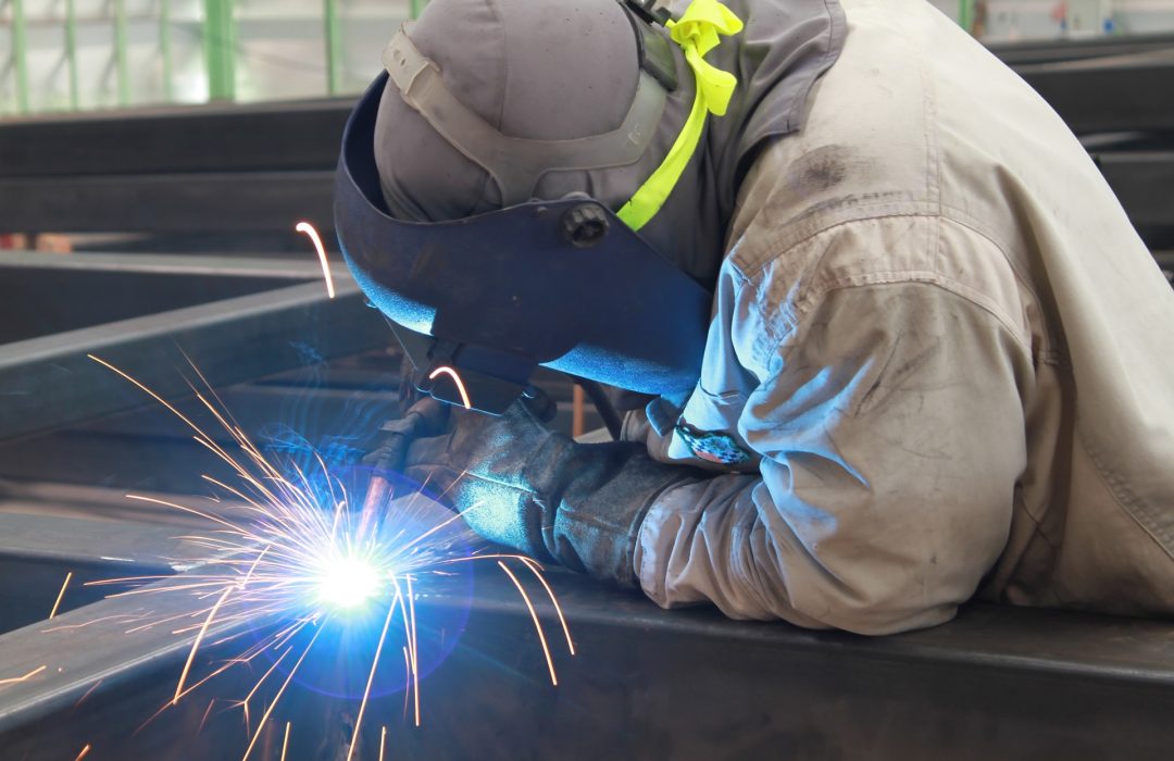 welder is welding steel structure with safety mask in factory